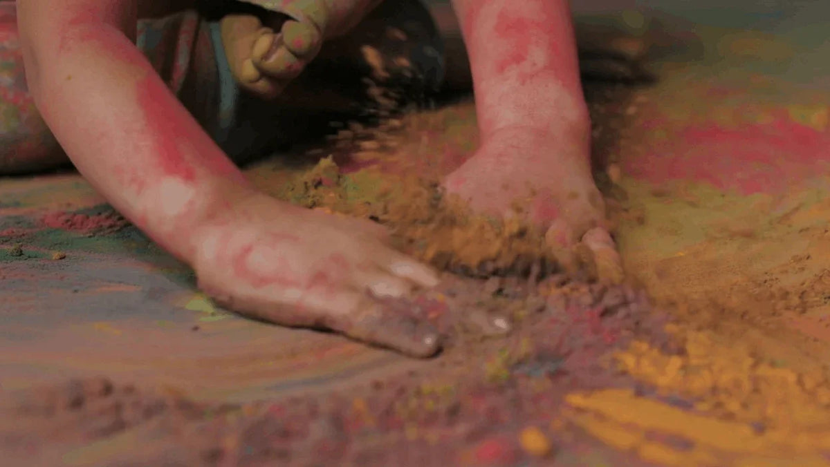 Child's hands playing with colorful powder on floor, symbolizing vibrant Vastu remedies