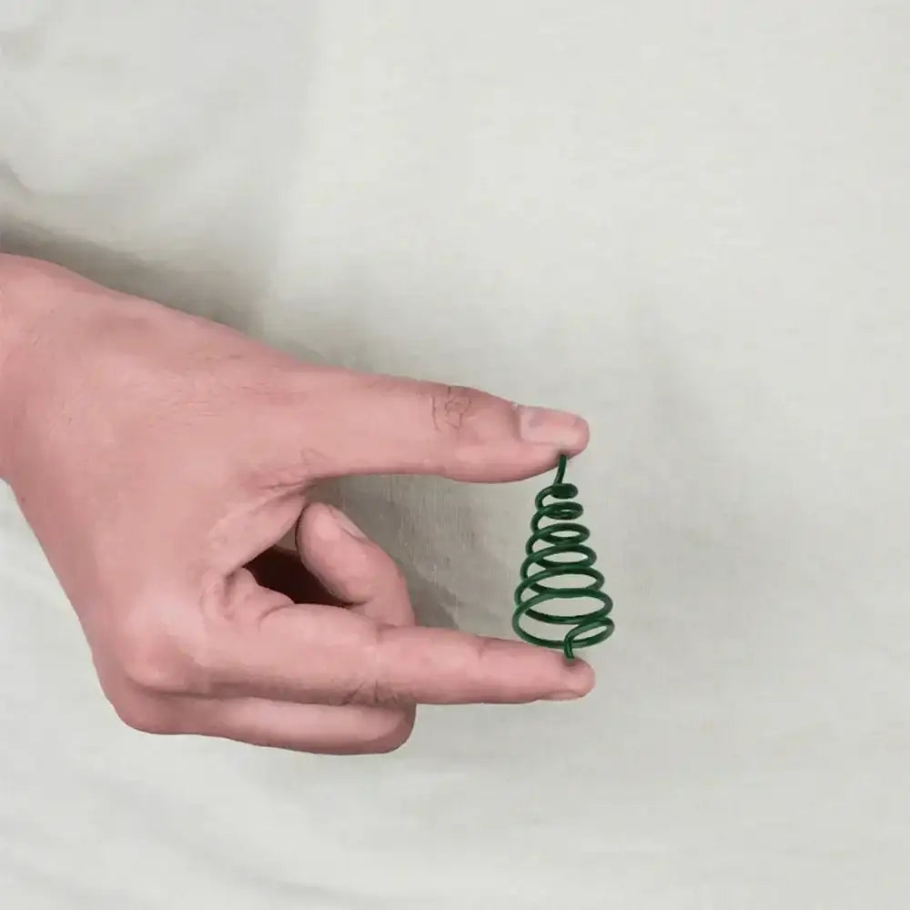 A person holding a small green spiral metal strip for Vastu remedies.
