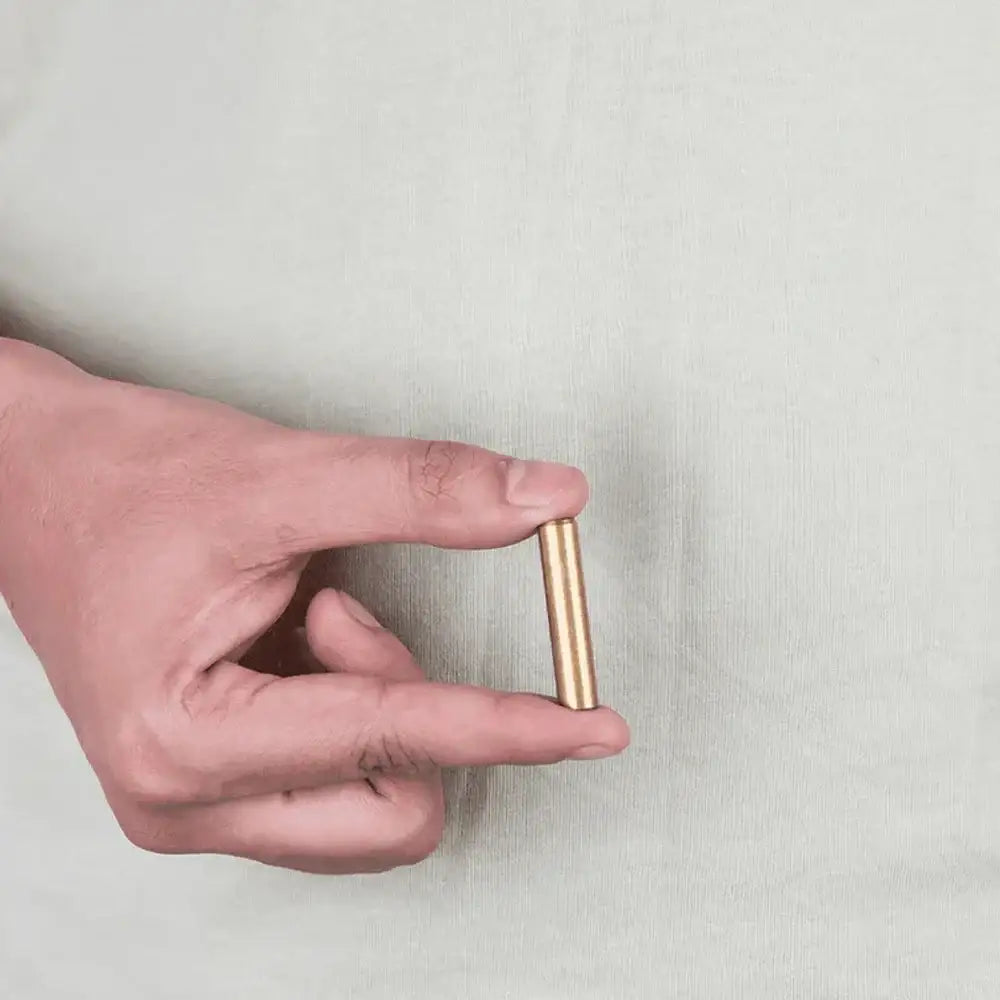 Hand holding small brass Vastu metal strip for home energy balance and positivity