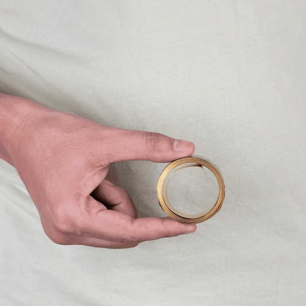 Hand holding MahaVastu brass metal strip remedy for Vastu Shastra balance and positivity