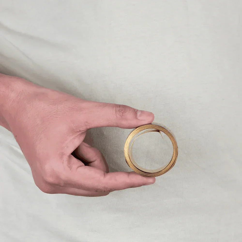 Hand holding MahaVastu brass metal strip remedy for Vastu Shastra balance and positivity