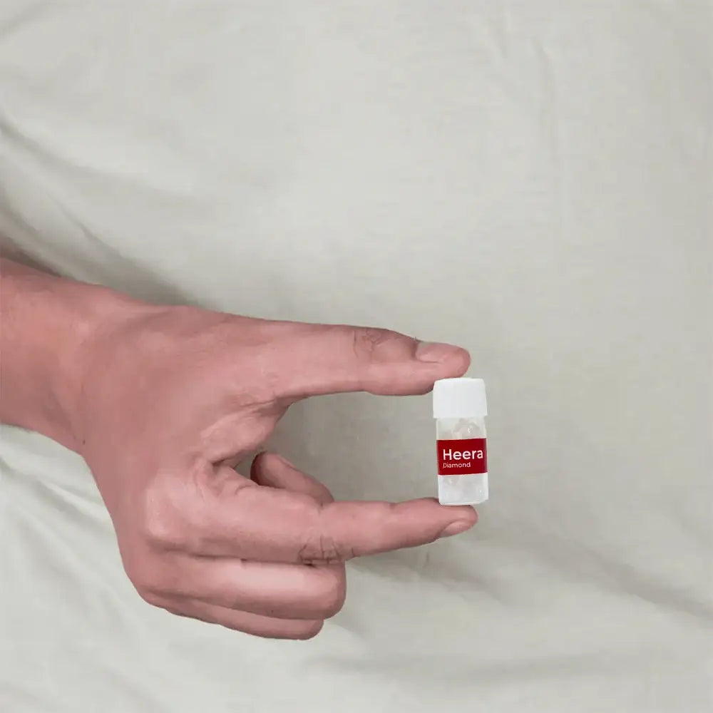 A hand holding a small vial labeled Heera Diamond for Vastu remedies.