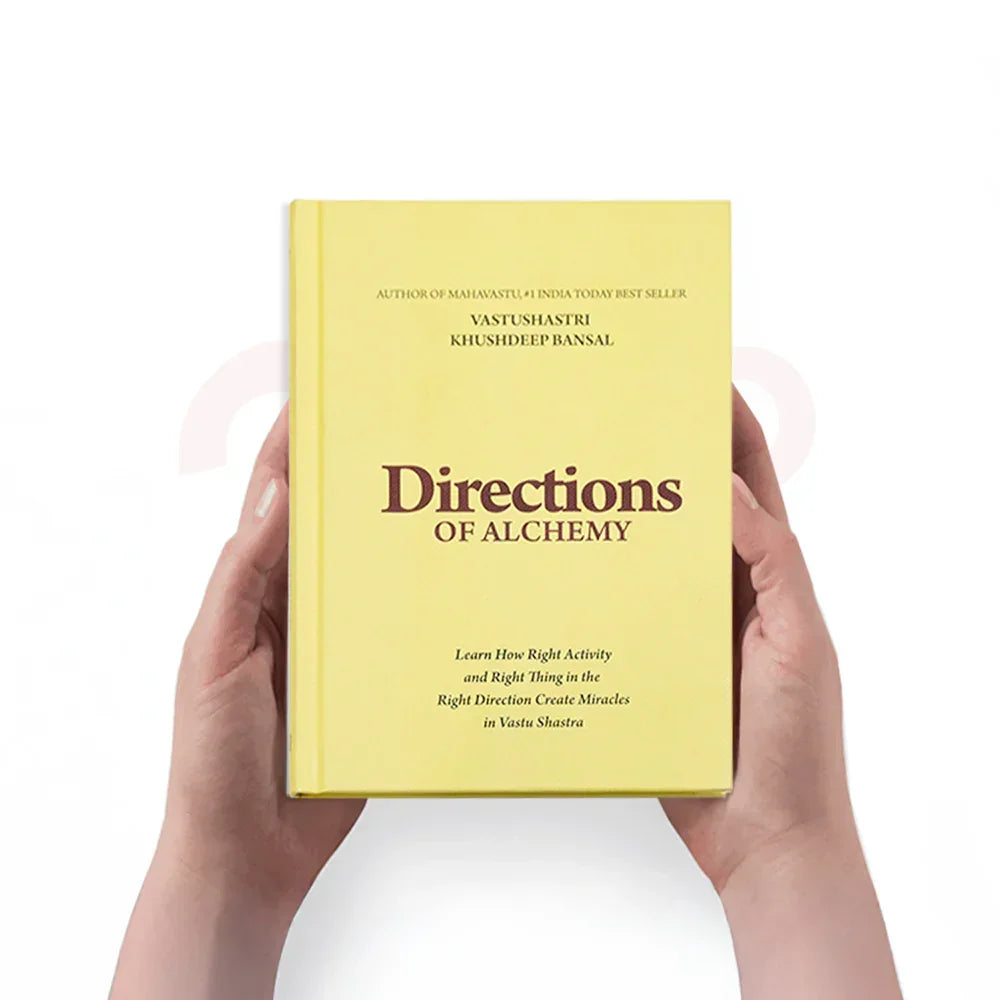 Person holding Vastu Shastra book titled Directions of Alchemy with yellow cover