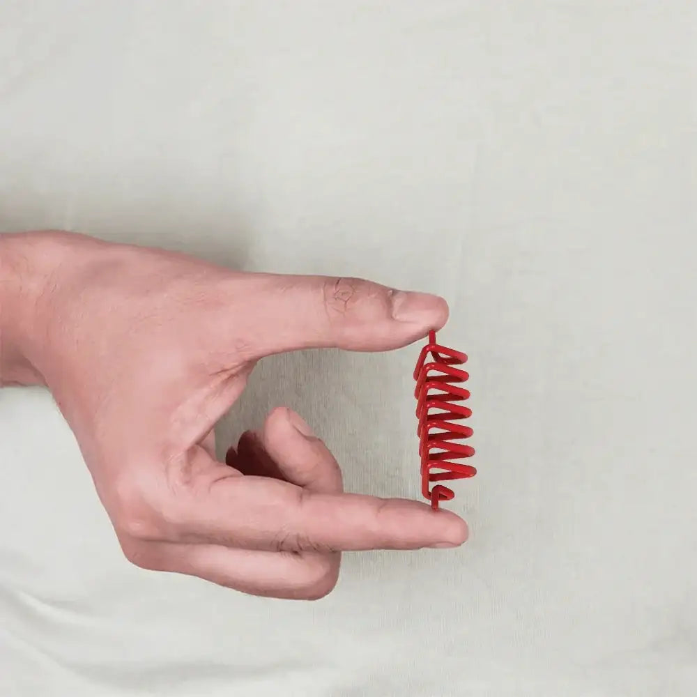 A person holding a small red Vastu color tape coil against a plain light background.