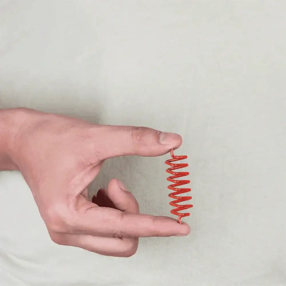 Hand holding a red metal strip for Vastu remedy application.