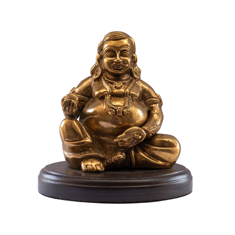 An intricately detailed golden statue of Yaksharaj Kuber, a Maha Vastu item for ohome, depicted seated on a dark base, adorned with heavy jewelry and holding a small object.