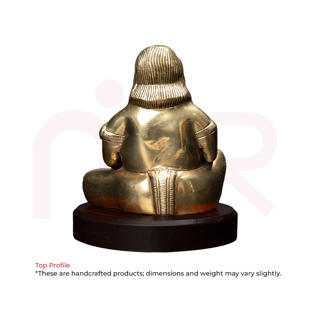 Back view of a brass Kuber idol seated on a wooden base, Vastu decorative item.