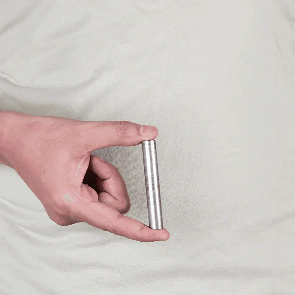 Hand holding MahaVastu iron metal strip remedy against light background