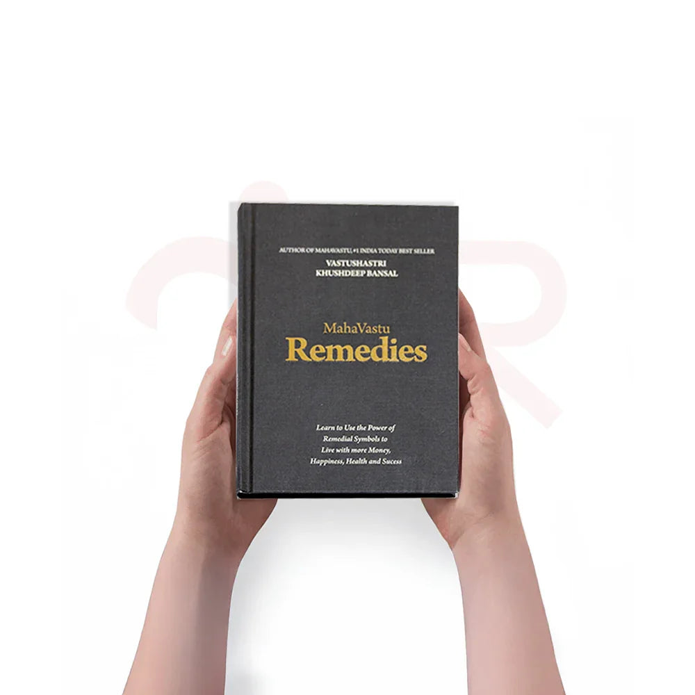 Hands holding the MahaVastu Remedies book, Vastu Shastra guide for money, health, and positivity.