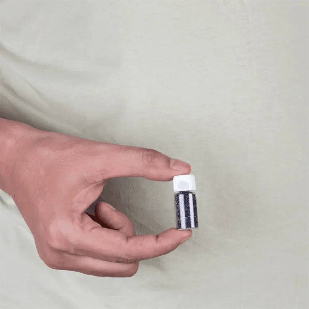 Hand holding MahaVastu remedy vial with black and white stripes for Vastu Shastra balance