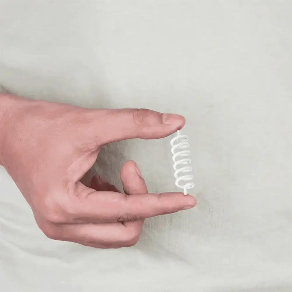 A hand holding a white spiral spring remedy for Vastu Shastra balance.
