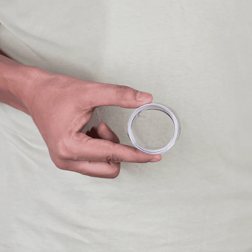 Hand holding stainless steel Vastu remedy metal strip against a light background