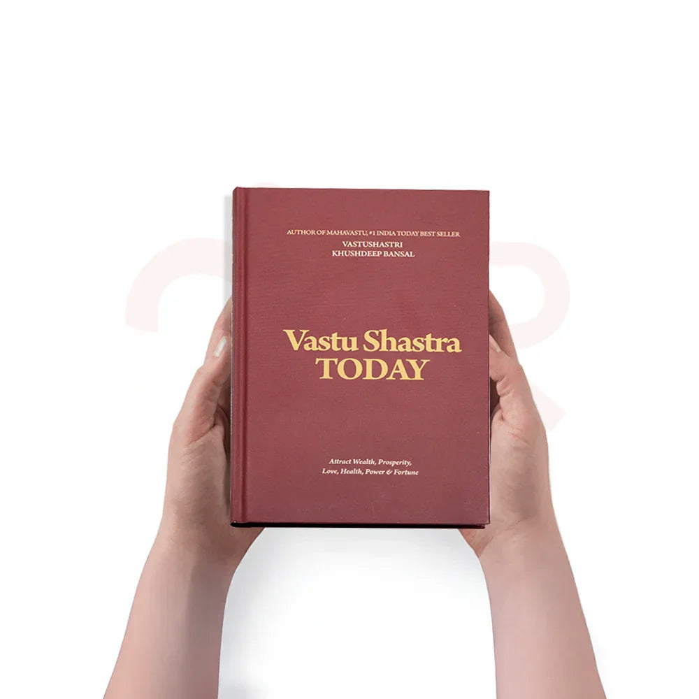 Hands holding 'Vastu Shastra Today' book, MahaVastu remedies, attract wealth and positivity