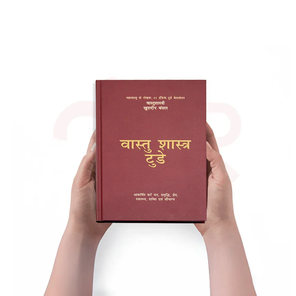 Hands holding a red Vastu Shastra Today Hindi book, MahaVastu remedies guide