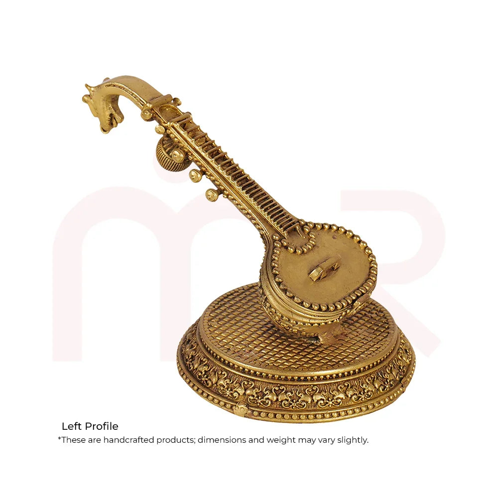 Handcrafted golden Veena idol for MahaVastu remedies, placed on an ornate round base.